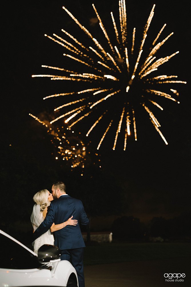A bride and groom kissing underneath fireworks