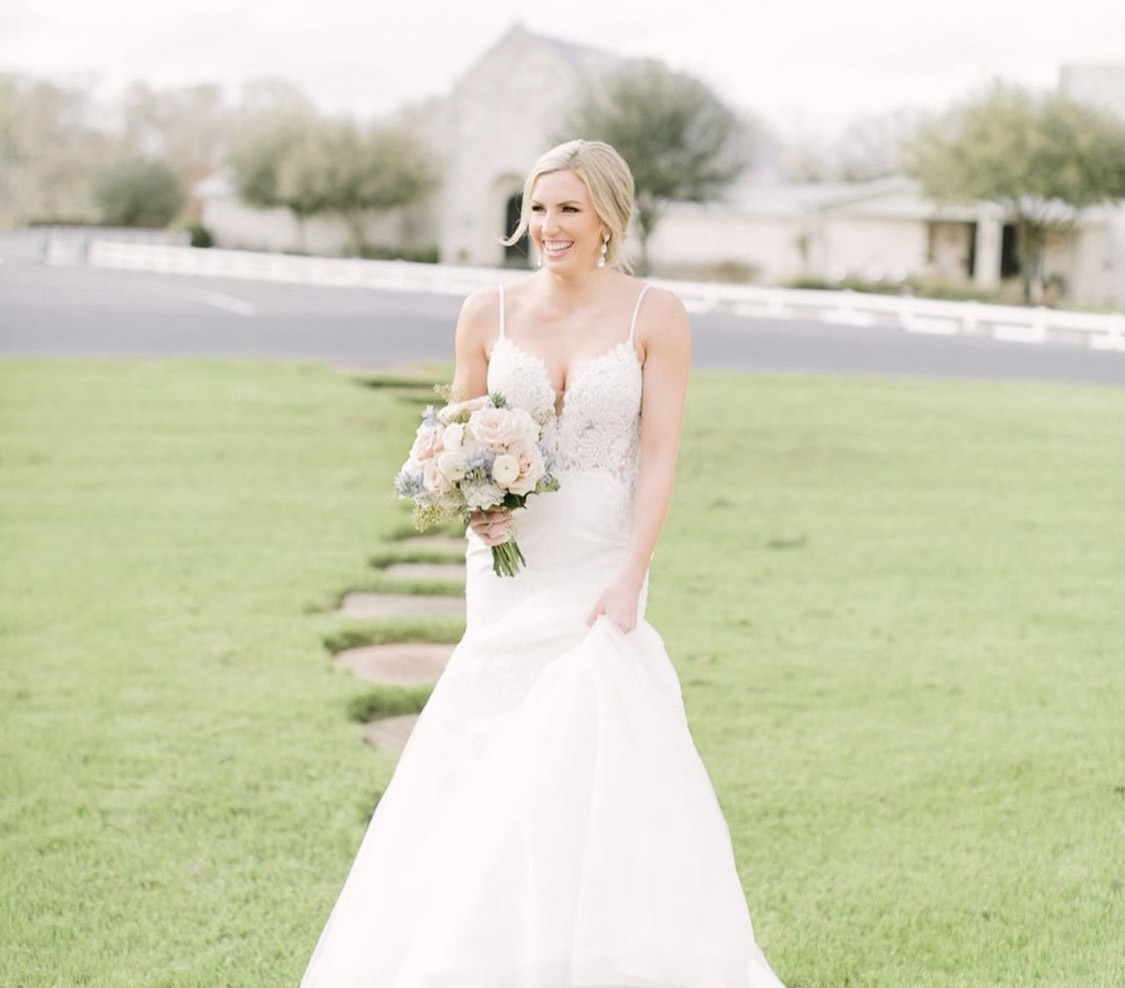 Blonde Bride holding bouquet walking down a stone path heading away from The Chapel