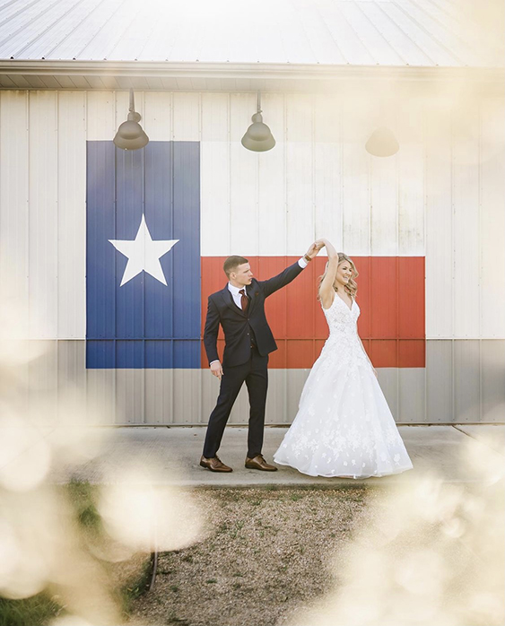 Bride and Groom dancing in front of a Texas flag.